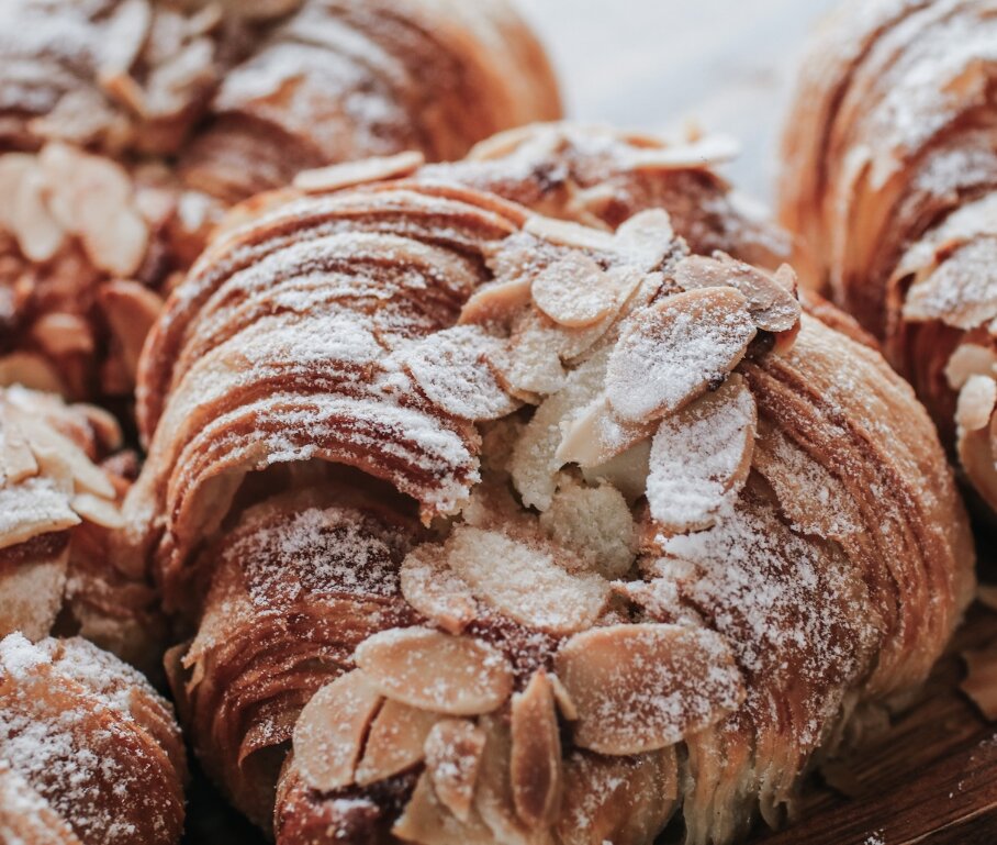 close up of freshly baked almond croissants with icing sugar and sliced almond on top